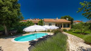 a swimming pool with umbrellas and chairs and a house at Villa MA by Villas Guide in Vodnjan