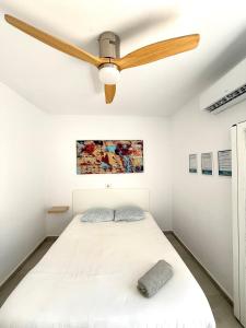 a white bedroom with a ceiling fan at Cisne By Nest Hostel in San Antonio