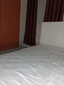 a white bed in a bedroom with red curtains at BR Homes 2 Bedroom in Bungoma +1 photo