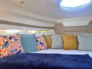 a bed in the middle of a room with pillows at Siesta Luxury Love Boat - NOCLEG NA ŁODZI W MARINIE SOLNEJ in Kołobrzeg
