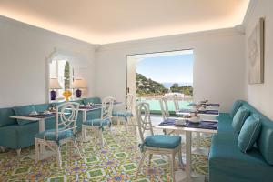 ein Wohnzimmer mit blauen Möbeln, einem Tisch und Stühlen in der Unterkunft Sina Flora in Capri