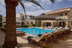 a pool with chairs and umbrellas next to a building at Maravel Star Art Hotel in Adelianos Kampos