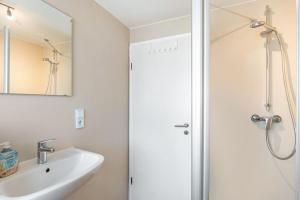 a white bathroom with a shower and a sink at Ferienwohnung Grodenblick in Hooksiel +12 photos