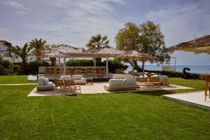 a group of lounge chairs and umbrellas on a lawn at Maravel Star Art Hotel in Adelianos Kampos