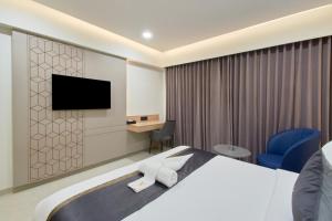 a hotel room with a bed and a flat screen tv at Hotel V Kondapur in Hyderabad
