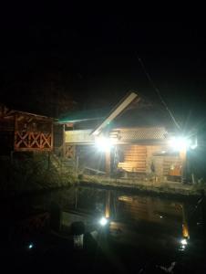 a cabin at night with two lights on at Котедж Перша Хата in Synevyrsʼka Polyana +15 photos