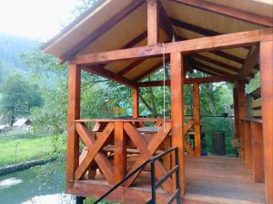 a wooden pavilion on the side of a body of water at Котедж Перша Хата in Synevyrsʼka Polyana