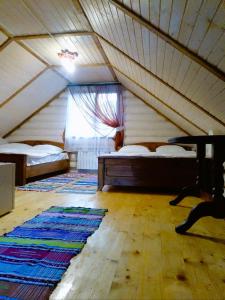 an attic room with two beds and a rug at Котедж Перша Хата in Synevyrsʼka Polyana