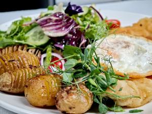 a plate of food with an egg and a salad at Hotel i Apartamenty Gorzelanny Dźwirzyno in Dźwirzyno