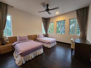 a bedroom with two beds and a ceiling fan at Riverview Bungalow in Cameron Highlands in Tanah Rata