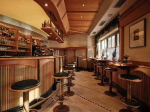 a bar with a row of stools in a room at Cityhotel Goldener Adler B&B in Chiusa