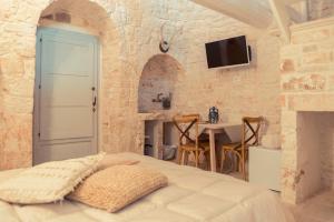 a bedroom with a bed and a table and a tv at Trulli diffusi de La Corte dell'Astore I Trulli Antichi Mestieri in Alberobello