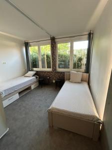a bedroom with two beds and two windows at La Parenthèse Gîte in Créhange