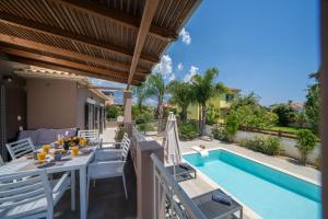 a patio with a table and chairs next to a swimming pool at Villa Malenia in Argostoli