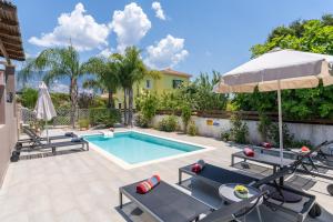 a pool with chairs and an umbrella next to a house at Villa Malenia in Argostoli