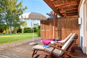 a patio with two chairs and an umbrella on a deck at Ayurveda Resort MANDIRA in Bad Waltersdorf