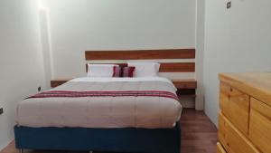 a bedroom with a bed and a wooden dresser at Intikilla House in Cusco