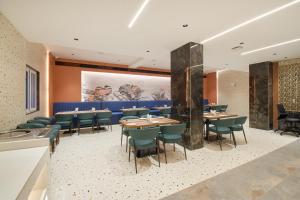 a restaurant with wooden tables and green chairs at Hotel V Kondapur in Hyderabad