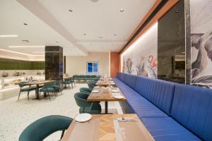 a dining room with wooden tables and blue booths at Hotel V Kondapur in Hyderabad