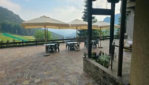 a patio with tables and chairs and umbrellas at Il rifugio della Presolana in Castione della Presolana