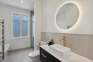 a white bathroom with a sink and a mirror at Modern home, old charm! in Lake Hāwea