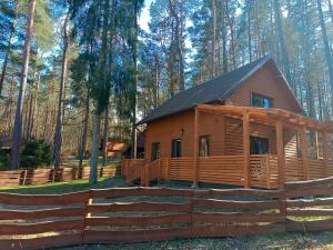 a log cabin in the woods with a fence at Domek nad Jeziorem 5 in Kamienica Królewska