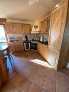 a kitchen with wooden cabinets and a tile floor at La Casa del SEI SERIO in Pieve di Cadore +8 photos