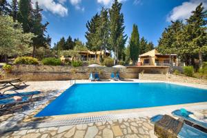 a swimming pool with chairs and a house in the background at Glyfada Beach Villas in Longós +48 photos