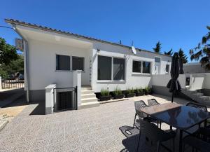 a white house with a patio with a table and chairs at Apartmani Antonela in Seline