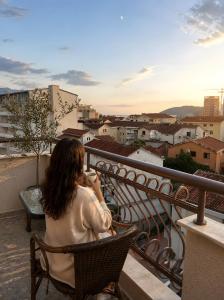a woman sitting in a chair on a balcony looking at the city at Hotel Fineso in Budva