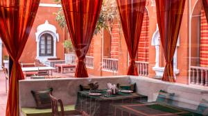 a restaurant with red curtains and tables and chairs at Garrison at Dera Bagseu in Bikaner