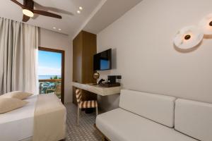 a hotel room with a bed and a desk and a window at Enavlion Elegance Seaside Luxury in Chrysi Ammoudia