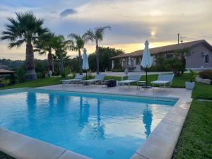 a swimming pool with chairs and umbrellas next to a house at Villa Concita in Noto