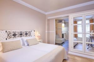 a white bedroom with a large white bed and a door at Apartamentos Luna Suites Palacio Almagra in Granada