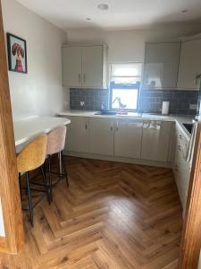 a kitchen with white cabinets and a wooden floor at The River Nook in Termonbarry