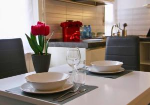 a table with two plates and wine glasses and flowers at Casa Calipso in Melzo