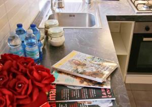a kitchen counter with books and flowers and water bottles at Casa Calipso in Melzo +2 photos