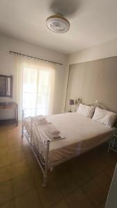 a bedroom with a white bed with a window at Erofili in Pefkochori
