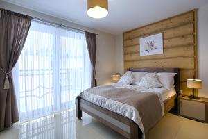 1 dormitorio con cama y ventana grande en Gordonówka Apartamenty & SPA, en Szaflary
