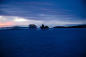 two people sitting in a tent on a large body of water at Villa Sarmi - a true off-the-grid hut in Inari