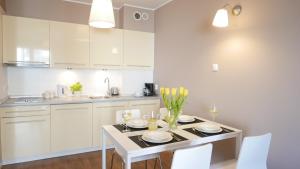 a kitchen with white cabinets and a table with chairs at Apartament Biały in Darlowko