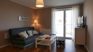 a living room with a couch and a table and a tv at Apartament Biały in Darlowko