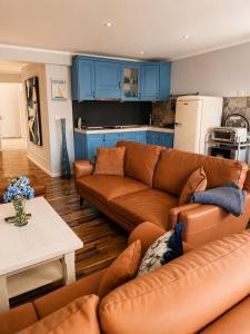 a living room with brown leather furniture and blue cabinets at Apartman Volosko in Opatija