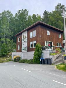 a large wooden building with a staircase next to a road at Leilighet ved vannet in Konsmo