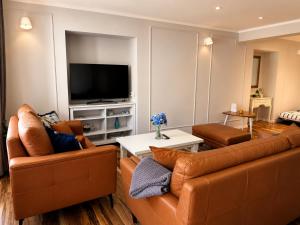 a living room with two leather couches and a television at Apartman Volosko in Opatija