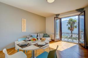 a living room with a table and chairs with a view of the ocean at 76 The Lake House - Lugano in Melide