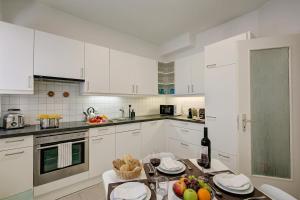 a kitchen with white cabinets and a table with fruit on it at 76 The Lake House - Lugano in Melide