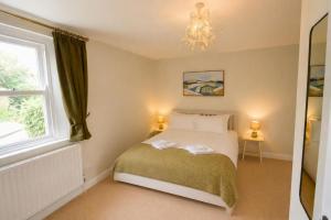 a bedroom with a bed with a chandelier and a window at Brookfield Cottages in Bakewell