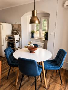 a kitchen with a white table and blue chairs at Apartman Volosko in Opatija +18 photos