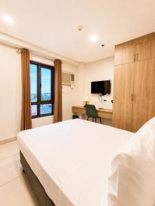a bedroom with a large white bed and a desk at Milton Hotel Makati in Manila +14 photos